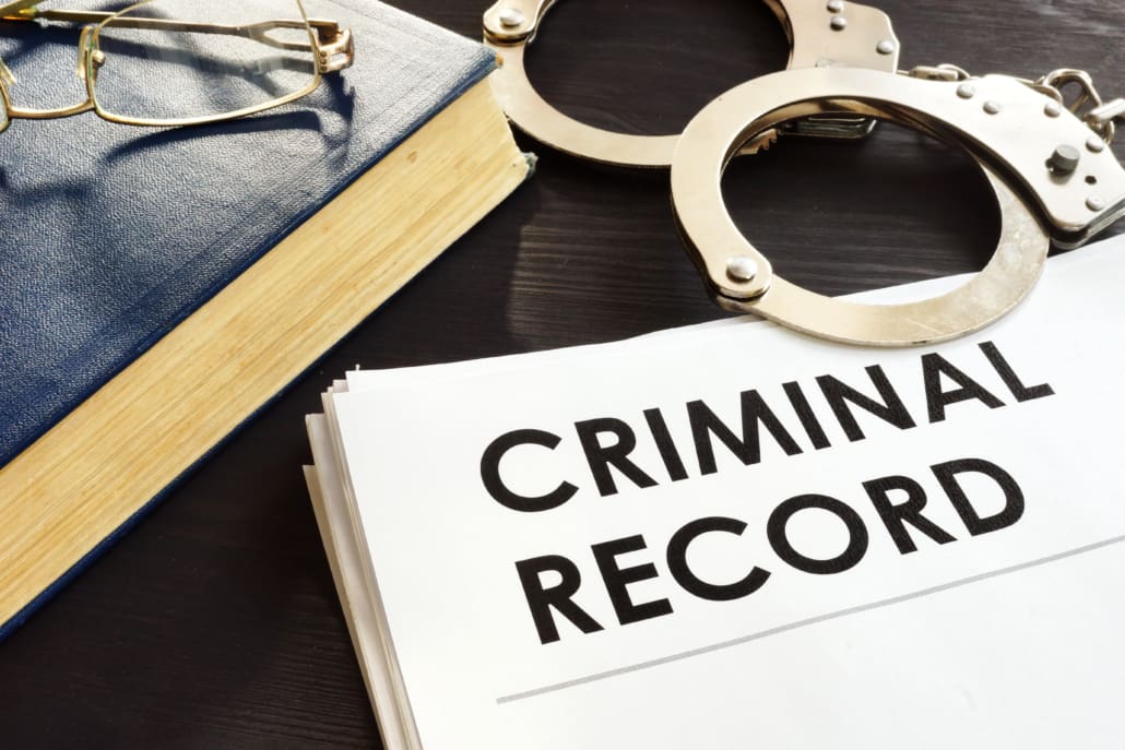 A dossier labeled "criminal record" alongside handcuffs and a legal book, symbolizing law enforcement and the legal consequences of criminal activity.